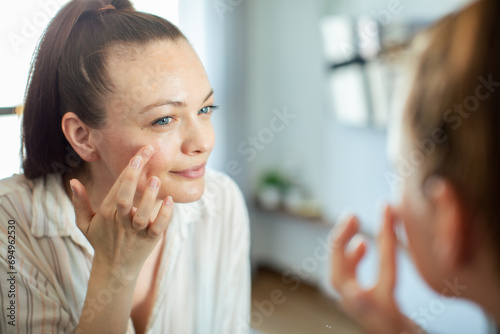 Young woman applying makeup with home mirror
