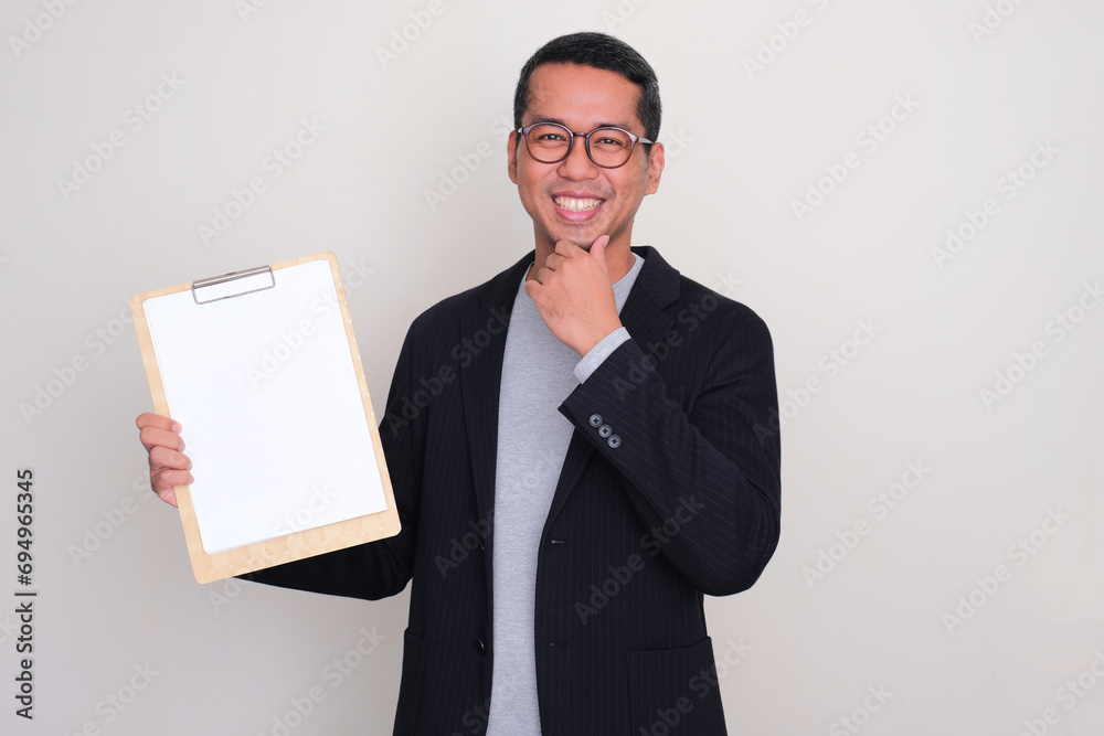 Asian casual businessman smiling happy while showing blank white paper on writing pad Asian casual businessman smiling happy while showing blank white paper on writing pad