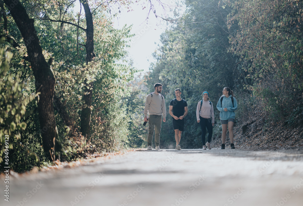 A group of friends hiking in an autumn forest, enjoying conversations, fresh air, and beautiful landscape. Healthy outdoor adventure with happy people in nature.