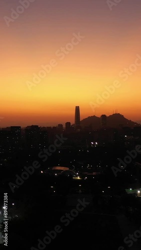 Sparkling Santiago City Silhouette at Sunset. Aerial View. Evening Twilight. Blue Hour. Las Condes Commune. Chile. Drone Flies Upwards. Vertical Video photo