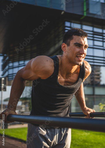 One man muscular male athlete training dips outdoor in sunny day