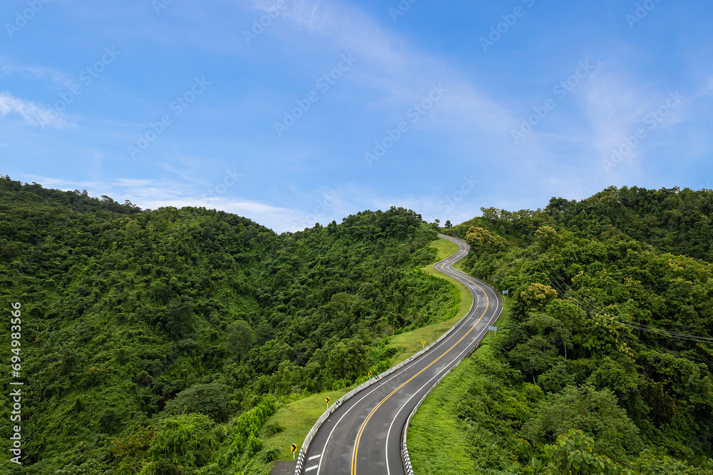 Aerial view of countryside road passing through the green forest and mountain in Thailand. Aerial view of countryside road passing through the green forest and mountain in Thailand.