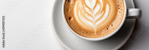 Wide panoramic top view photo of a Cappuccino coffee cup with cream design on it and a saucer in white background photo