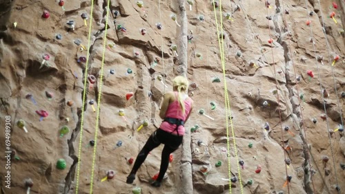 Back of woman downing with special equipment on climbing wall photo