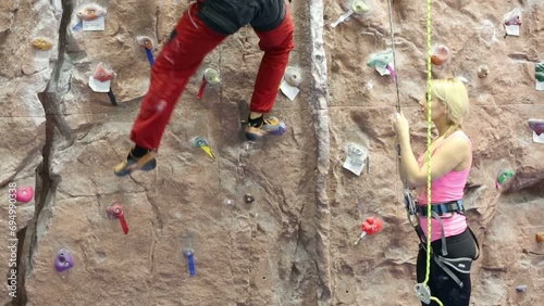 girl looks at instructor teaching to climb on climbing wall photo