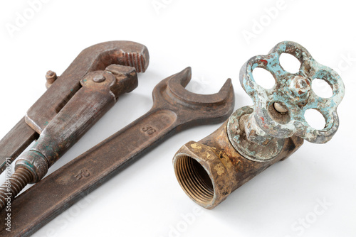 disassembled old water faucet with wrenches for dismantling, plumbing work concept, on isolated white background