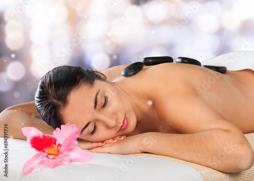 Woman enjoying hot stones massage in spa