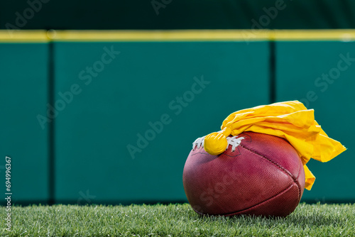 Fotografía An American football with a yellow penalty flag sitting on top