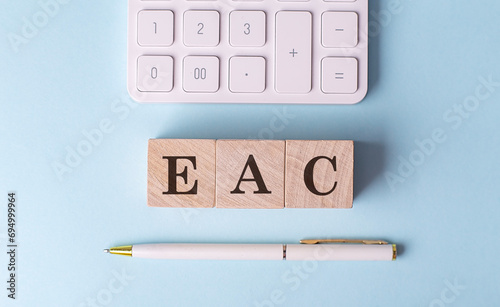 EAC on wooden cubes with pen and calculator, financial concept