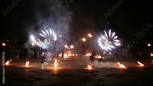 Two girls dance with burning fans in foreground at street photo