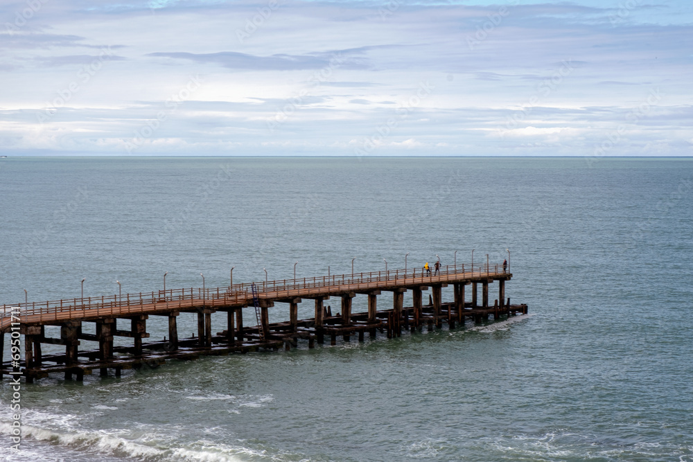 Abandoned small Black sea pier. Calm sea water under low cloudy sky Abandoned small Black sea pier. Calm sea water under low cloudy sky