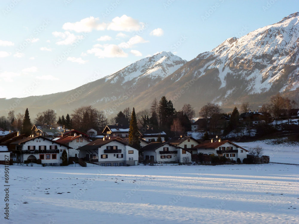 The houses of the ski hotel are located under the mountain covered with forest and snow. Winter landscape