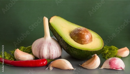 Ripe avocado and garlic are on the table. Green background. Red pepper. Still life. soft focus photo