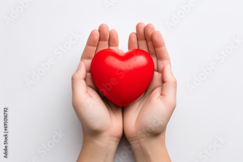 Hands holding a red heart against a white background.