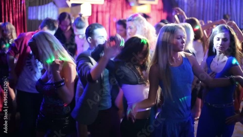Eighteen young people have fun and dance at party in night club photo