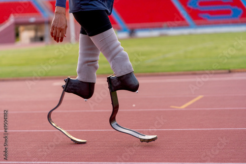 Side view of sport man athlete prosthesis legs stand and warm up legs on track in the stadium.