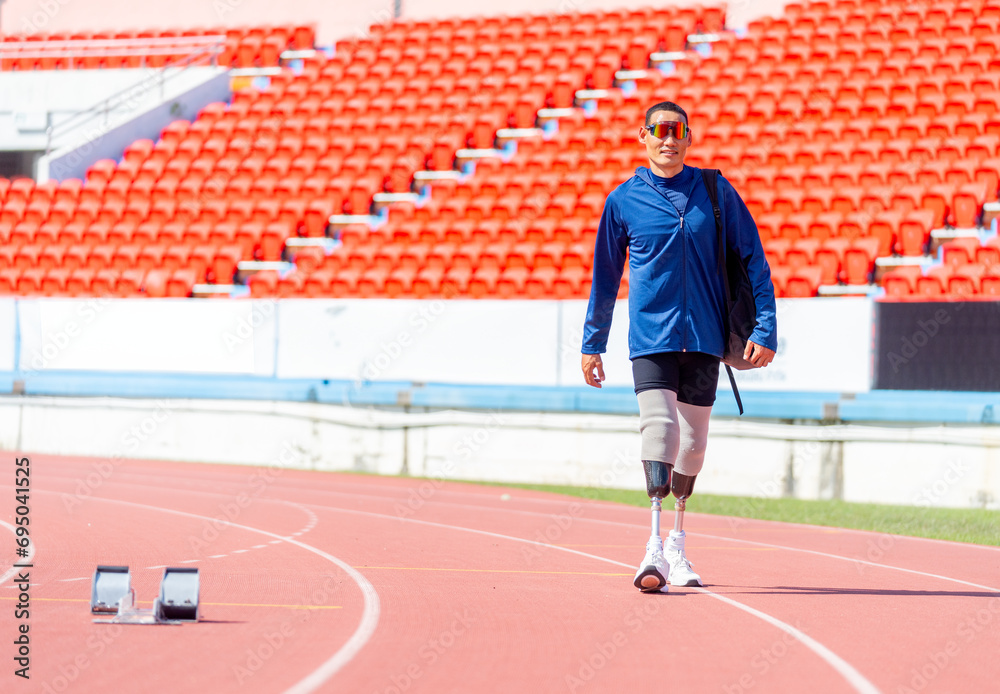 Sport man athlete prosthesis legs with sun glasses carry the bag and walk on the track of the stadium with day light.