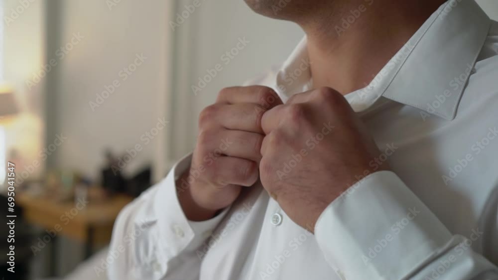 Man puts on white shirt and buttoning. Morning of the groom on the wedding day, the person dresses for a party, holiday or event. Businessman wears suit.