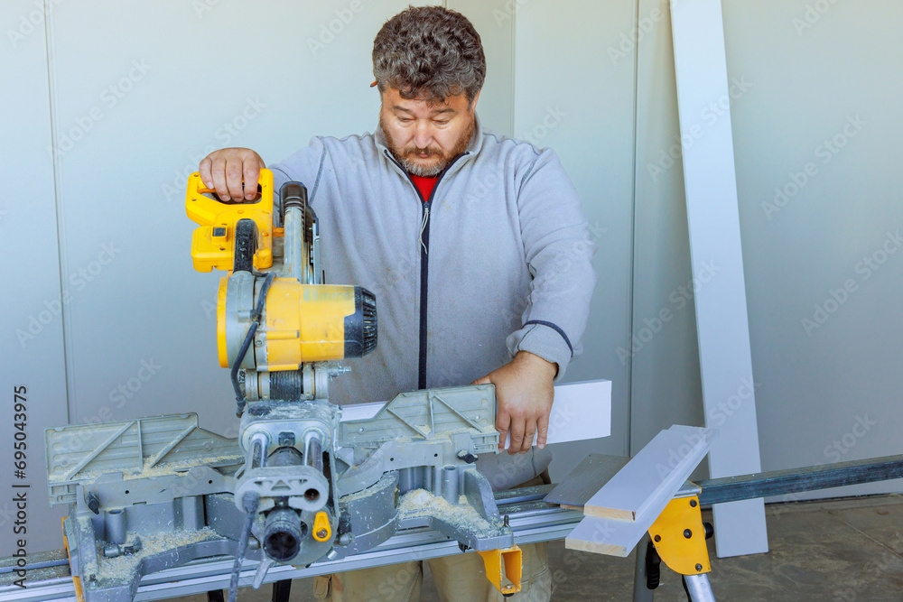 Using chop saw trim worker cuts wood base molding using chop saw Using chop saw trim worker cuts wood base molding using chop saw