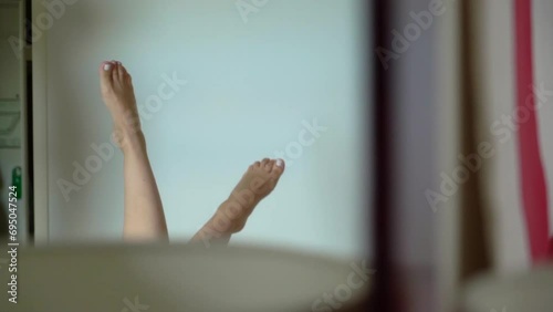 Woman laying in bed raise her naked legs up. Feet reflection in a mirror. photo