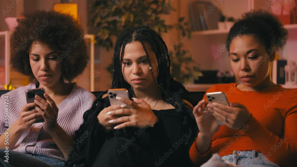 Three African American women use their phones on couch ignoring communication Three African American women use their phones on couch ignoring communication