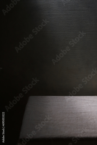 Empty table is covered with linen tablecloth on dark background.