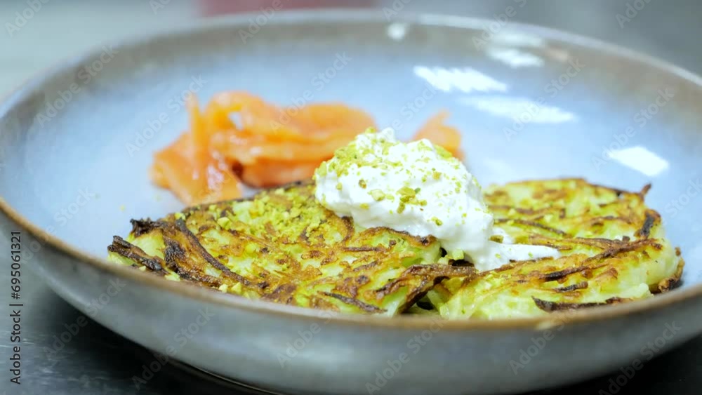 Ready dish in the restaurant kitchen, potato pancakes with red fish on a plate, the chef is serving the dish, squash cakes with fish Ready dish in the restaurant kitchen, potato pancakes with red fish on a plate, the chef is serving the dish, squash cakes with fish