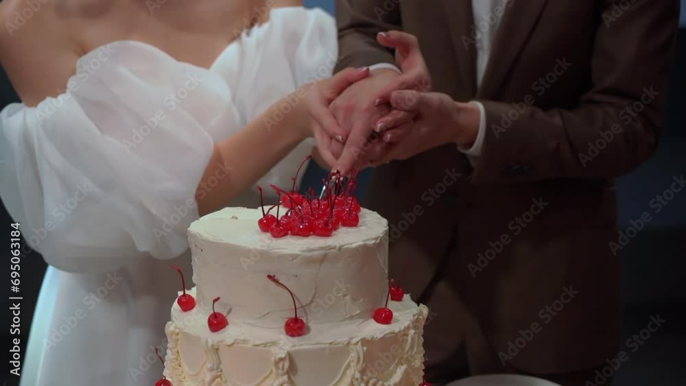 A person cutting a celebration cake. Bride and groom at wedding reception venue. Man and woman holding knife and cut a slice of dessert. A person cutting a celebration cake. Bride and groom at wedding reception venue. Man and woman holding knife and cut a slice of dessert.