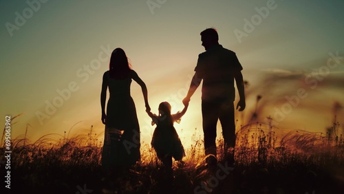 Man and wife take girl to field to practice family yoga. Man with beloved wife walking in fresh evening air of park with little daughter. Man with wife and daughter finally gets out for walk © SUPER FOX