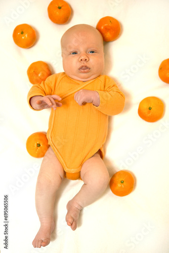 Little child with tangerines in an orange suit