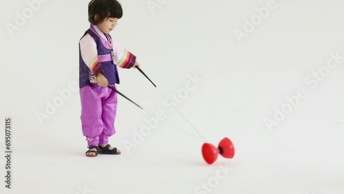 Little boy in korean silk suit plays with diabolo toy in studio photo