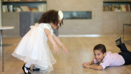 Cute boy and girl dance and fall to floor in business center photo