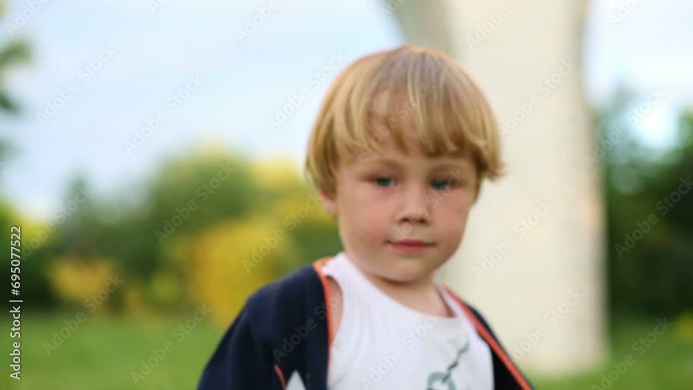 Little blond boy nods his head and smiles at summer day outdoor Little blond boy nods his head and smiles at summer day outdoor