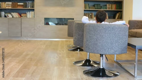 Cute mulatto boy in jacket turns in armchair in business center photo