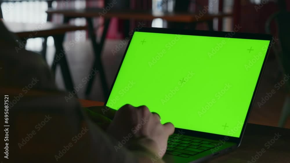 A close-up of a green screen for integrating the media of a programmer's laptop, which is working writing code in the dark interior of a cafe. Remote work on a laptop in a coworking space. 4k footage A close-up of a green screen for integrating the media of a programmer's laptop, which is working writing code in the dark interior of a cafe. Remote work on a laptop in a coworking space. 4k footage