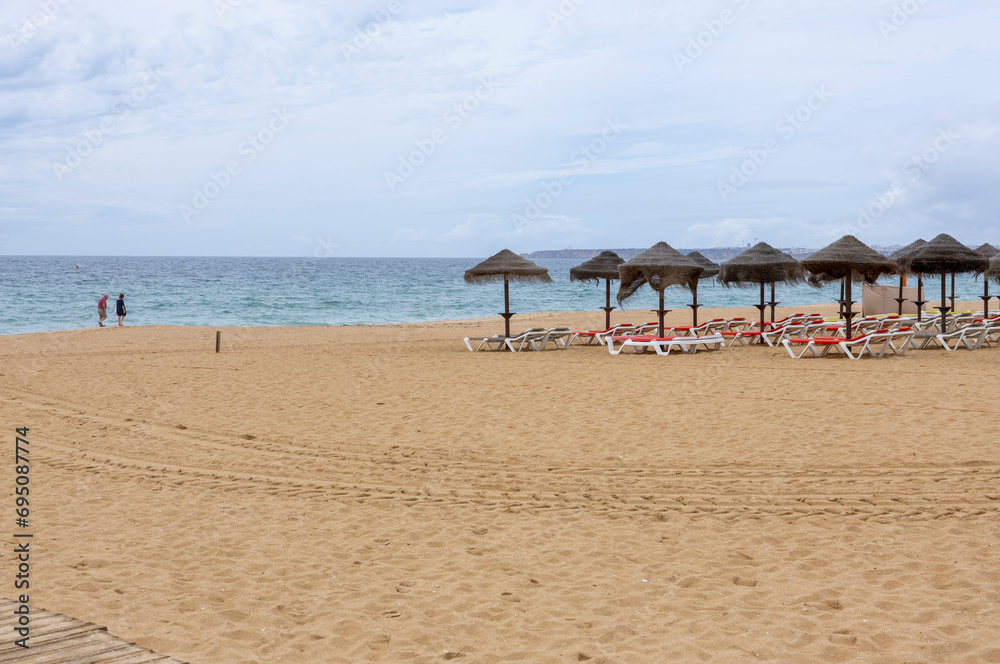 Beach with empty sunbeds and umbrellas on a beach in the Algarve, Portugal