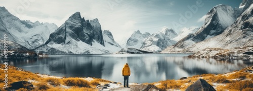 a person standing by a lake with mountains in the background