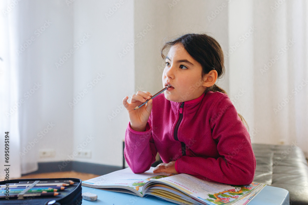 portrait of thoughtful girl sitting at the desk doing homework portrait of thoughtful girl sitting at the desk doing homework