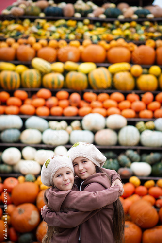 two sisters in autumn near a mountain of pumpkins photo