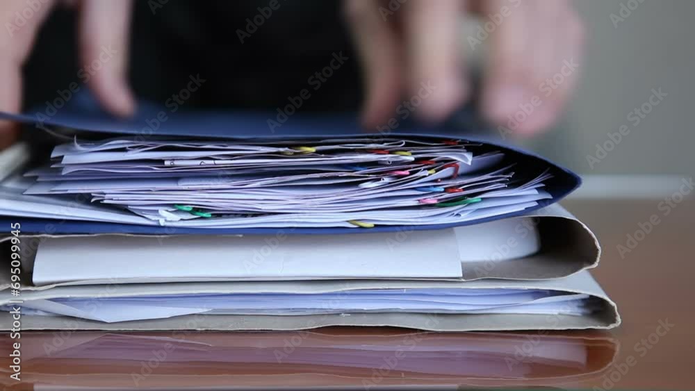 The man brings a large stack of documents to the table and reviews them. The man is rummaging through papers. Documents in the office on the table.