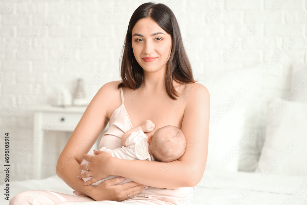 Young woman breastfeeding her baby in bedroom Young woman breastfeeding her baby in bedroom