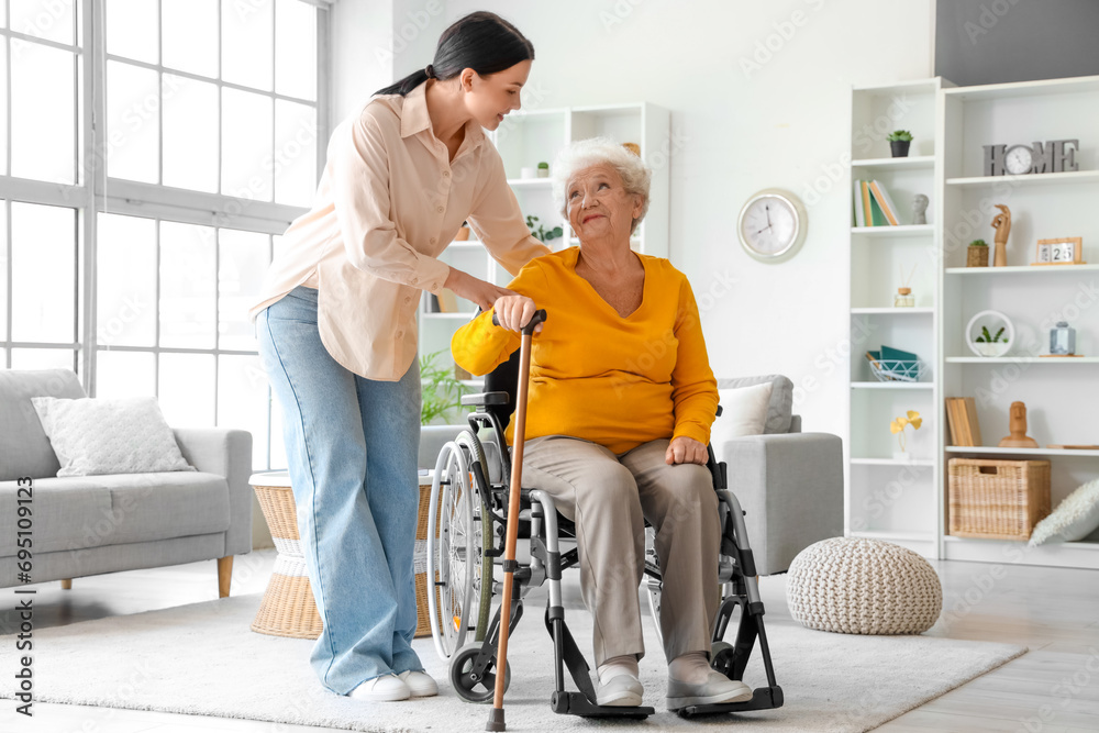 Senior woman in wheelchair with stick and her daughter at home - obrazy, fototapety, plakaty 