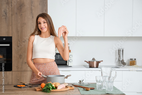 Young woman cooking soup wi...