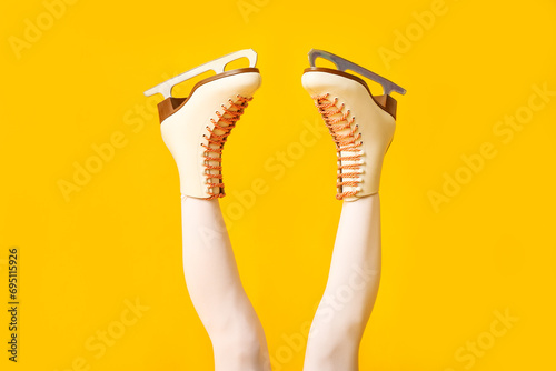 Legs of female figure skater in ice skates on yellow background photo