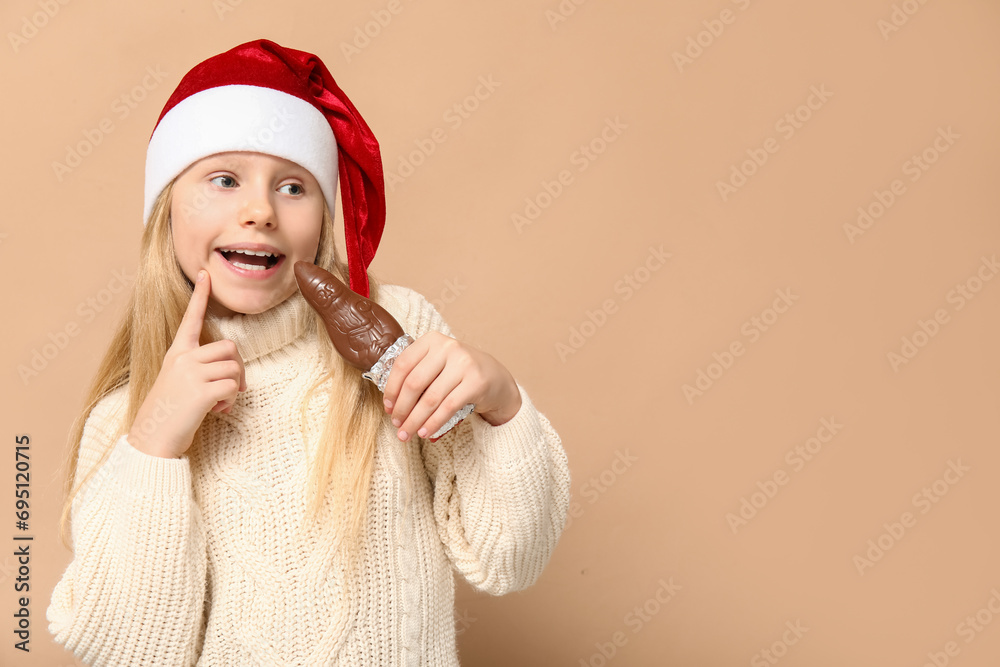 Cute little girl with chocolate Santa Claus on brown background Cute little girl with chocolate Santa Claus on brown background