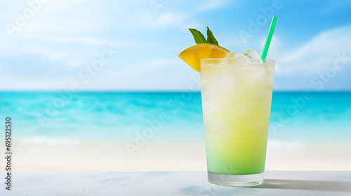 Refreshing cold tropical fruit punch drink garnished with lemon slice on a table and sandy beach and sea view. Cold refreshing summer  Background for summer vacation and travel.