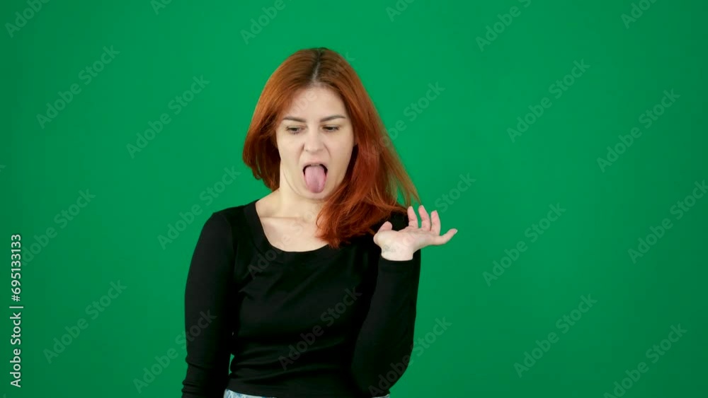 disgust dissatisfied facial expression stick out tongue gagging Reflex woman with red hair distorts her face with a grimace negative emotions smile at the end on a green background person disgust dissatisfied facial expression stick out tongue gagging Reflex woman with red hair distorts her face with a grimace negative emotions smile at the end on a green background person