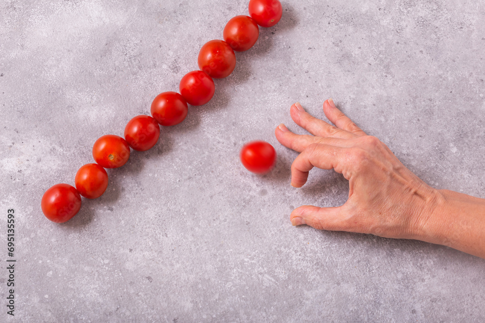 Playing with cherry tomatoes for accuracy on the table. Womans hand and cherry tomatoes, closeup with selective focus