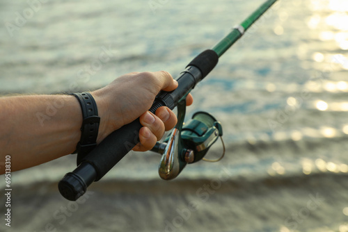 Fisherman with rod fishing at riverside, closeup. Space for text