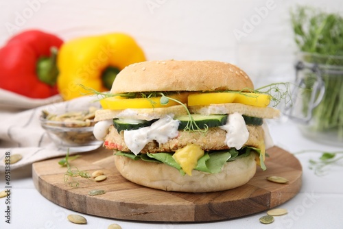 Tasty vegan burger with vegetables, sauce and patty on white table, closeup